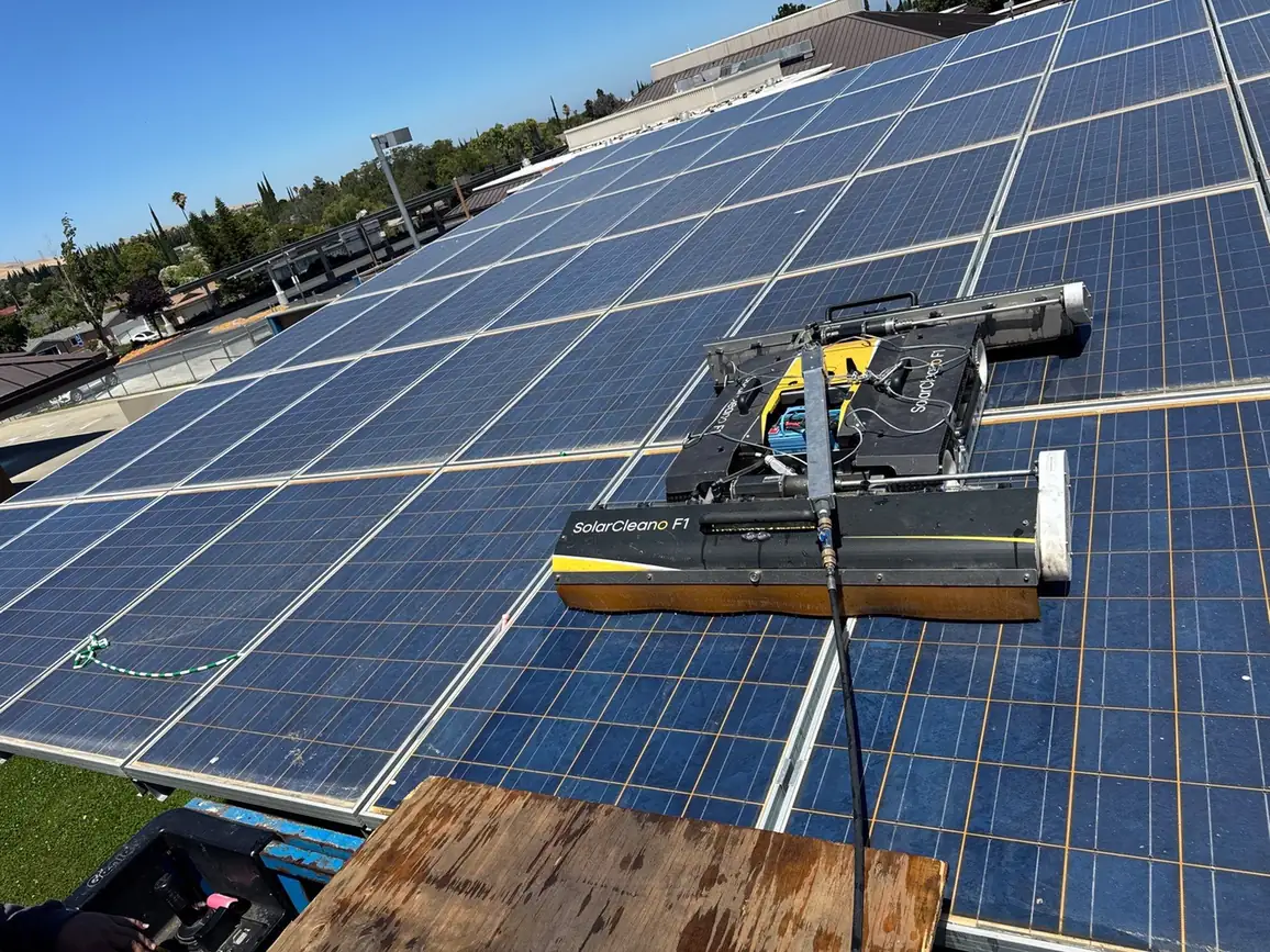 SolarCleano F1 robotic cleaner mid-pass on a low-tilt school district solar carport canopy, Pittsburg CA